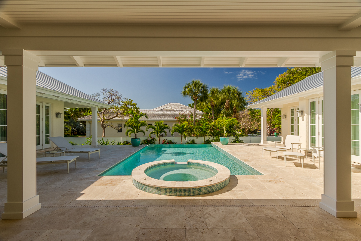 A photo of a pool, lounge chairs, and the outdoor area it resides in.